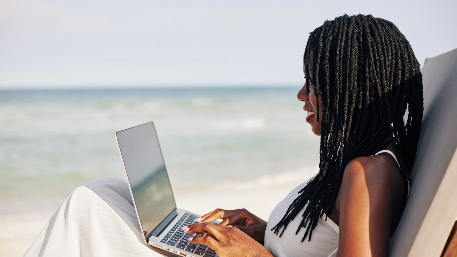 Woman working on a laptop on the beach, relevant to retirement planning