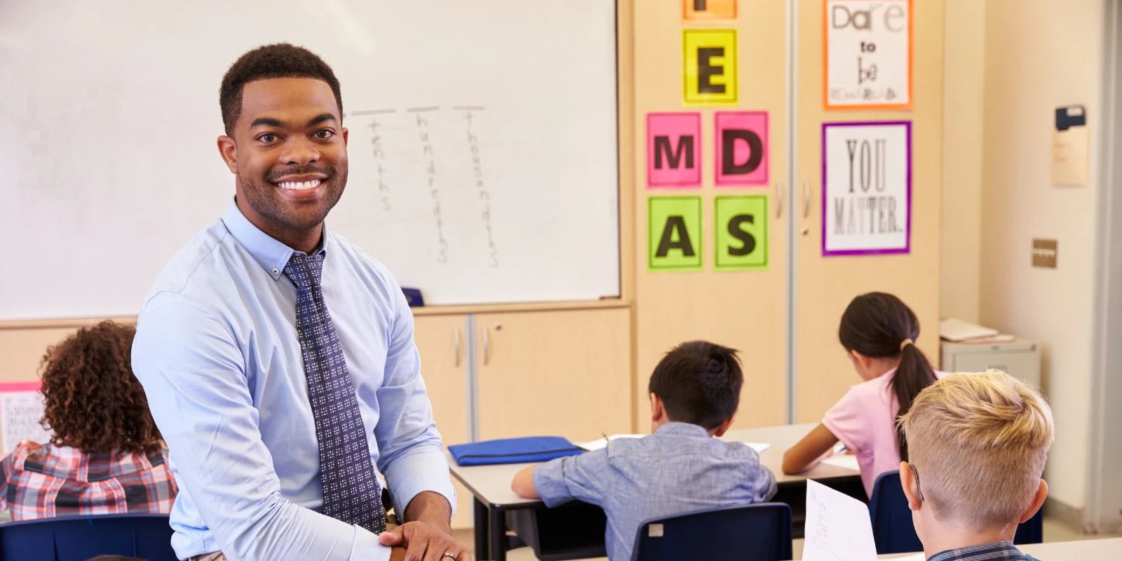 Young American teacher smiling in Thai school classroom for expat tax article